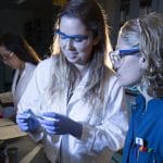 A student and a professor examine a sample in a lab.