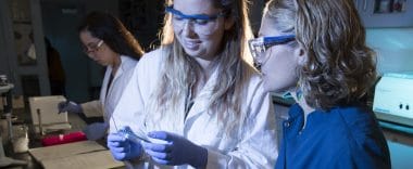 A student and a professor examine a sample in a lab.